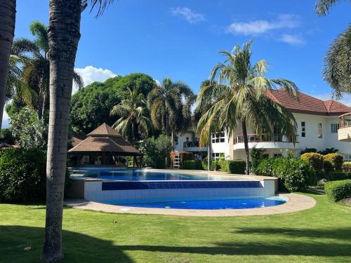 a swimming pool in front of a house with palm trees at Luxuary 1 Bedroom Apartment Pool and Sea view in Dauin in Dauin