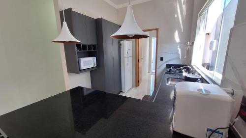 a kitchen with a black counter top and two lights at Ótima casa Termas Olímpia in Olímpia