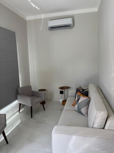a white living room with a couch and a chair at Ótima casa Termas Olímpia in Olímpia