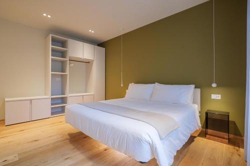 a bedroom with a large white bed with a green wall at Villa Amelia in Orta San Giulio