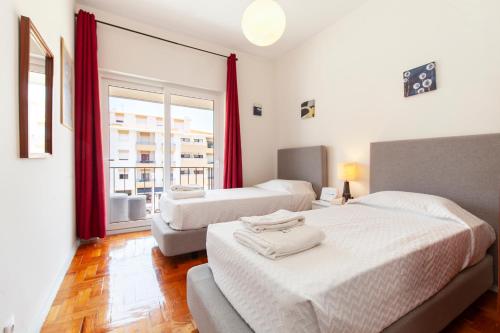 une chambre avec deux lits et une grande fenêtre dans l'établissement Trindade Sun Guesthouse, à Lagos