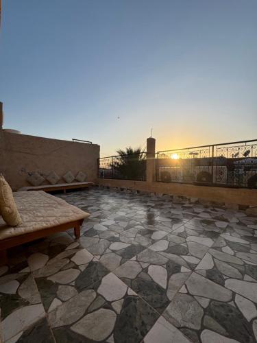 eine Terrasse mit einer Bank und einem Sonnenuntergang im Hintergrund in der Unterkunft Riad Tamounte piscine palmeraie in Marrakesch