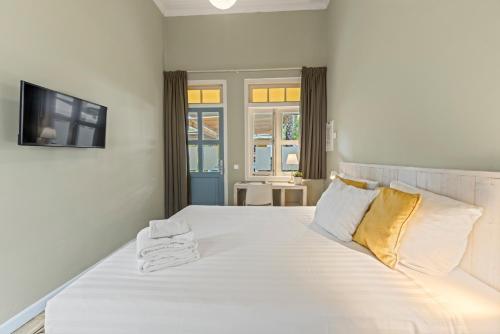 a white bed with two pillows and a television at Boutique Hotel 't Klooster in Willemstad