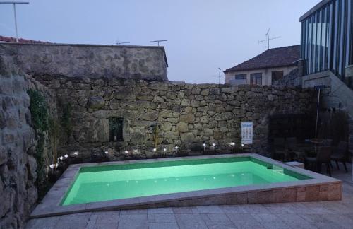 a swimming pool in front of a stone wall at Aquénio do Ouriço in Sernancelhe