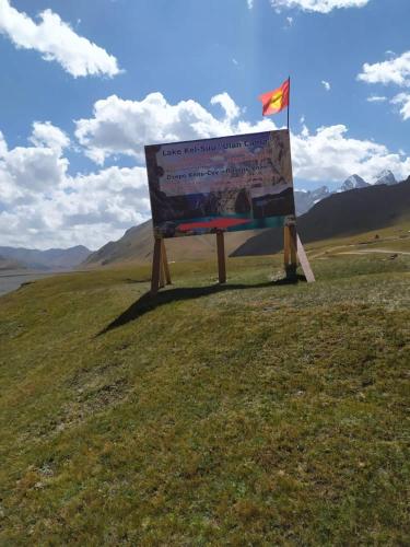 a sign in the middle of a field with a flag at Ulan Camp in Kol-Suu