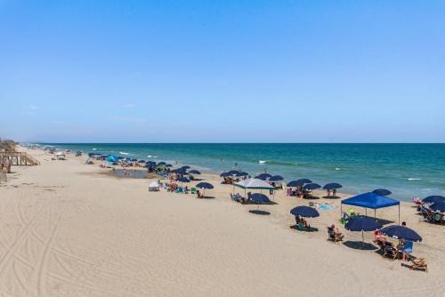 a group of people sitting on a beach with umbrellas at Animal House in Corolla