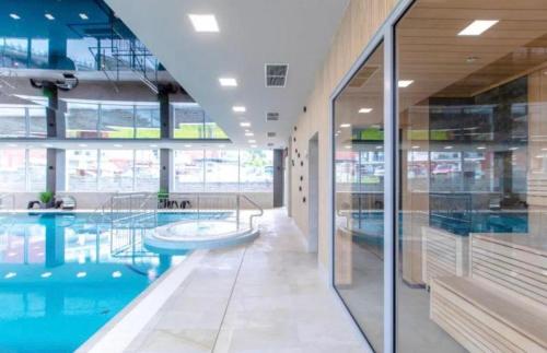 a swimming pool in a building with glass walls at Klifowa Apartament Premium in Rewal