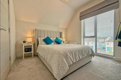 a bedroom with a bed with blue pillows and a window at Stylish apartment in Portstewart in Moffat