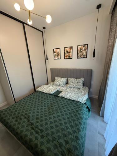 a bedroom with a bed with a green comforter and pillows at Klifowa Apartament Premium in Rewal