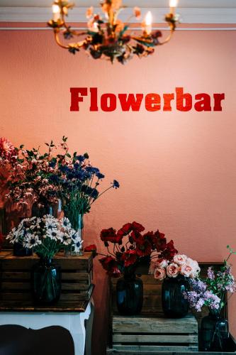 a sign that says flowerbar on a wall with flowers in vases at Tastecelebration Residence in Andrarum-Brosarp