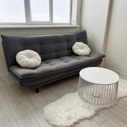 a living room with a couch with pillows and a table at A cozy and bright studio apartment in Chornomorsk
