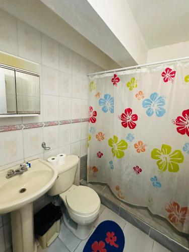 a bathroom with a toilet and a sink and a shower curtain at Aparthotel Michaela in Sosúa