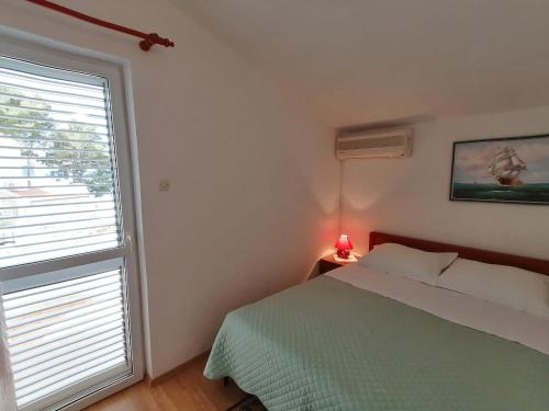 a bedroom with a bed and a window with a lamp at Apartman Dide in Igrane