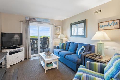 Una sala de estar con un sofá azul y un televisor. en Aquaholic, en Kill Devil Hills