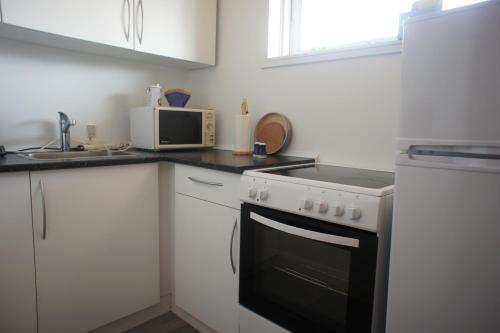 a white kitchen with a stove and a microwave at Tordenskjoldsgade 1 3 sal balkon 2 id 174 in Esbjerg