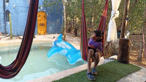 プエルト・モレロスにあるIf you enjoy nature, La Quinta Azul is the place, connecting with your sensesのプールの横のハンモックに座っている少年