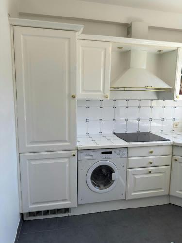 une cuisine avec des armoires blanches et une machine à laver dans l'établissement Marilyn Beach - Vue mer, terrasse, garage privé, à Cannes