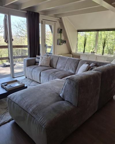 a large couch in a living room with windows at bungalow 199 durbuy in Durbuy