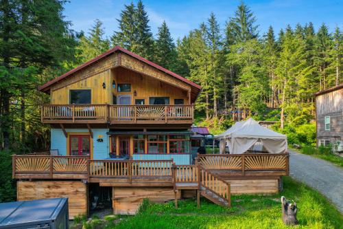 a large wooden house with a deck and a tent at Salmon Return and Wildlife Roam Ketchikan Getaway! in Ketchikan
