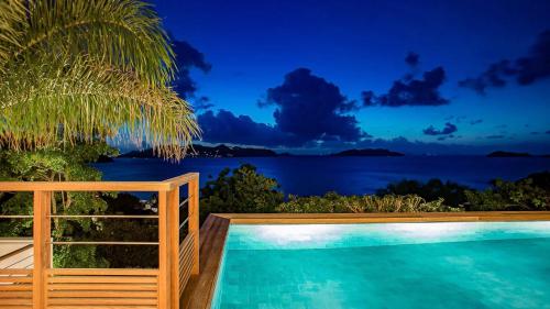 a pool with a view of the ocean at night at Four-Bedroom Sunset Villa with Infinity Pool in Pointe Milou