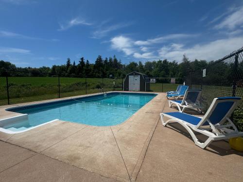 une piscine avec deux chaises longues à côté dans l'établissement Silverwood Motel, à Cavendish