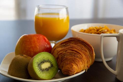 a plate of fruit with a croissant and a glass of orange juice at Park Hôtel & Appartements in Cholet