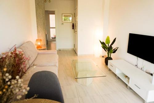 a living room with a couch and a flat screen tv at Bajo con jardines cerca de la playa in Miengo