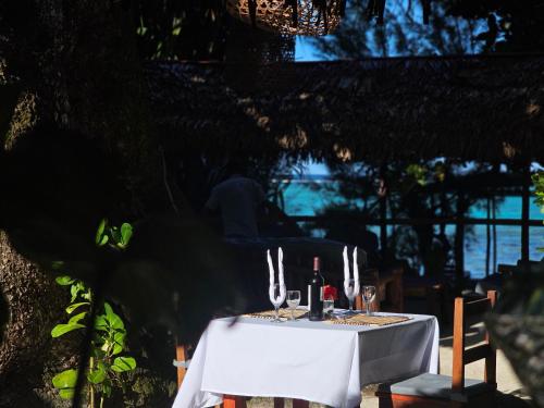 a white table with wine bottles and glasses on it at KINTANA LODGE in Ile aux Nattes