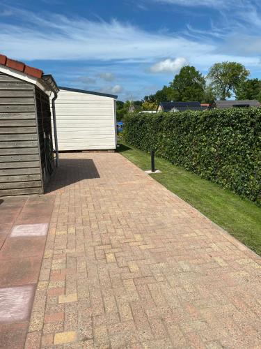 a brick driveway next to a building and a hedge at hûske twa in Oudwoude