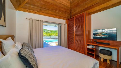a bedroom with a bed and a tv and a window at St Jean Hilltop Three-Bedroom Villa with Pool in Gustavia
