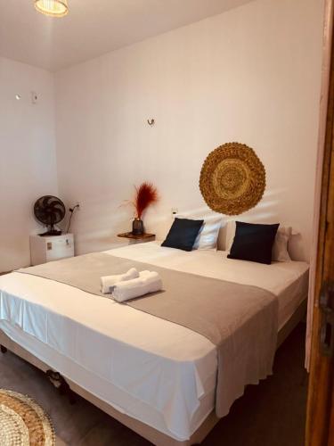 a bedroom with a large white bed with towels on it at Lu Pousada Charme Preá in Prea