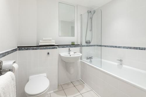 a bathroom with a toilet and a sink and a bath tub at Marlin Apartments London City - Queen Street in London