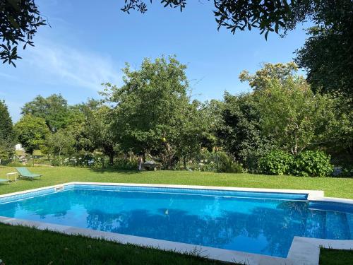 a blue swimming pool in a yard with trees at Quinta da Maínha - Charming Houses - Escape to Nature in Braga