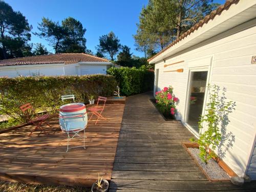 une terrasse en bois à côté d'une maison avec une chaise dans l'établissement LANDES CHALET 8 personnes, à Lit-et-Mixe