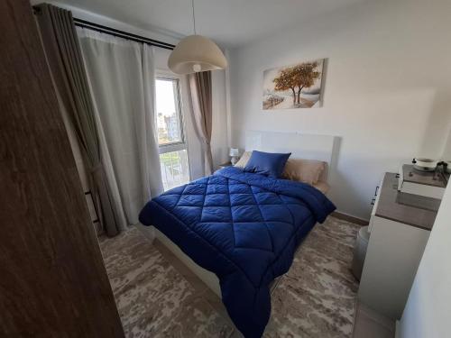 a bedroom with a blue bed and a window at Modern City Apartment in Cairo