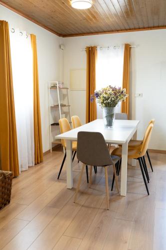 a white table with chairs and a vase of flowers on it at Geres Andorinhas House in Vieira do Minho