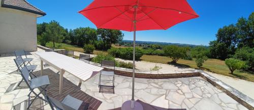 een rode parasol op een patio met een tafel en stoelen bij Grande Périgourdine, très grand jardin au calme in Bergerac