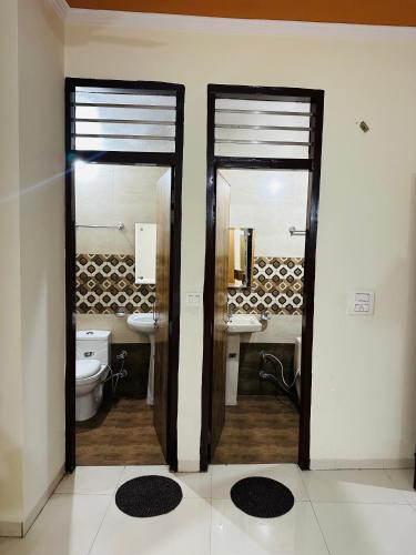 a bathroom with two mirrors and a toilet and sink at Hotel Victoria INN in Sohāna