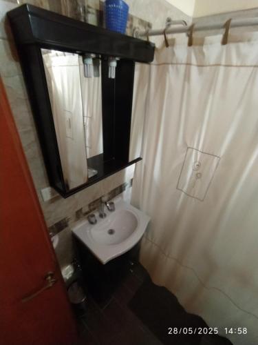 Un baño con una cortina de ducha blanca y un lavabo. en Casa de Nico, en Buenos Aires