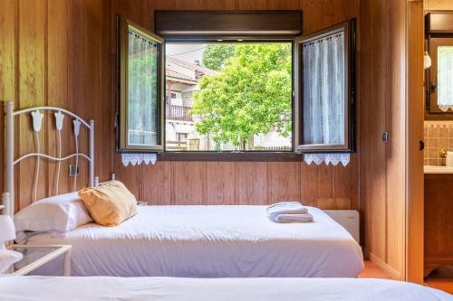 two beds in a room with a window at La casuca del norte in Hornedo