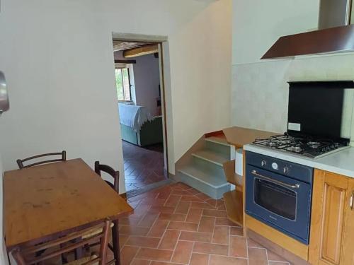 Una cocina con estufa y mesa y un comedor. en Casa dell Ulivo, en Castiglion Fiorentino