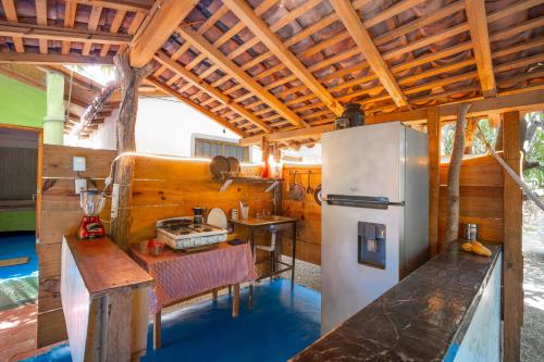 a kitchen with a refrigerator and a table at Mahue Rooms and Camping in Puerto Escondido