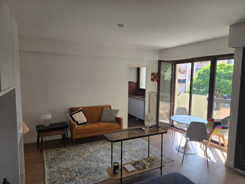 una sala de estar con un sofá y una mesa en Fully-equipped large studio with terrace, en Rueil-Malmaison