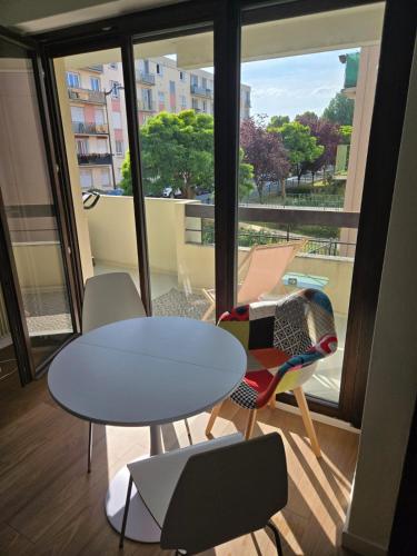 une table et des chaises dans une pièce avec une grande fenêtre dans l'établissement Fully-equipped large studio with terrace, à Rueil-Malmaison