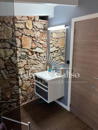 La salle de bains est pourvue d'un mur en pierre et d'un lavabo. dans l'établissement Terre de Caliso, à Carnoules