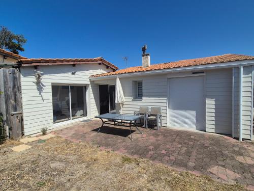 un patio avec une table et des chaises devant une maison dans l'établissement Maison LICORNE MARINE à 2 minutes à pied de la mer, à Lacanau