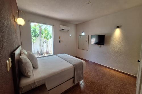 a bedroom with a bed with a window and a television at Capital O Hotel Rolovi Cancún in Cancún