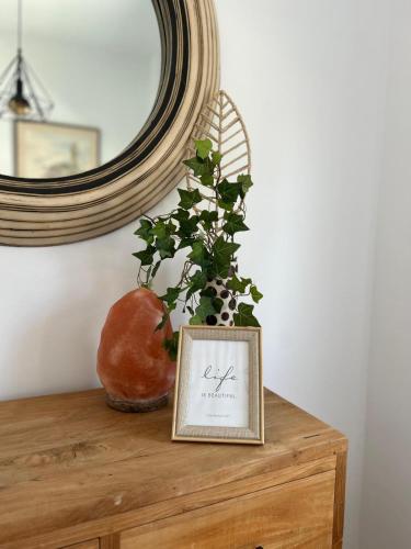 a picture on a wooden table with a plant and a mirror at Teak Charm in Larnaka