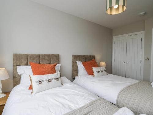 two beds in a room with white and orange pillows at The Hayloft in Calne