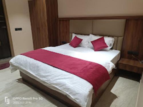 a large bed with red and white sheets and pillows at Jaiswal Dharmshala in Sultānpur